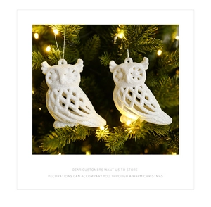 Detail of white owl Christmas tree ornaments with glitter finish and warm LED lighting