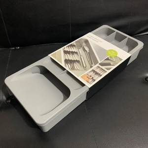 Macro view of grey expandable cutlery organizer with multiple compartments for drawers