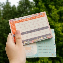 Handheld view of back to school timetable planner and cartoon notepad in a natural setting