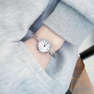 Detail of silver twisted cable cuff watch with roman numerals on woman wrist