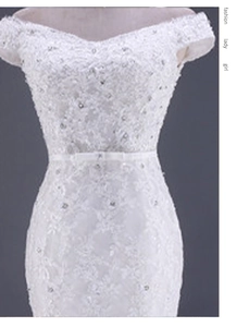 Dettaglio dell'abito da sposa in pizzo a spalle scoperte con paillettes e cintura in raso