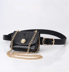 Detail showing a black faux-crocodile leather mini waist bag with a gold chain and turn-lock
