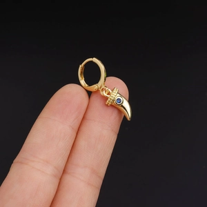 Detail of gold hoop earring with blue gemstone horn pendant held between fingers