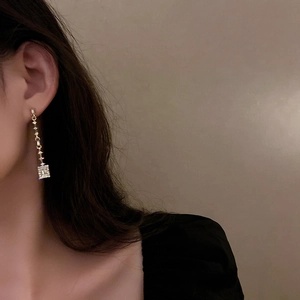 Elegant gold drop earrings with square zircon crystals on a model for luxury style