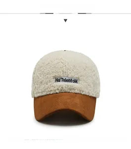Detail of white faux shearling baseball cap with brown suede brim and letter embroidery