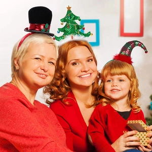 Close-up of festive Christmas headbands including tree and elf hat on happy people