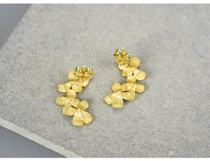 Macro shot of S925 sterling silver golden flower stud earrings with matte petal texture