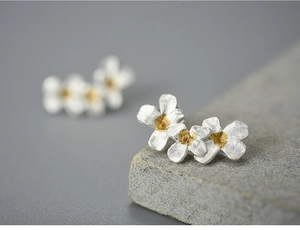 Detailed macro shot of S925 sterling silver flower earrings with matte gold center