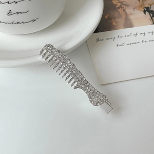 Close-up of comb-shaped silver hair clip with white sparkling rhinestones