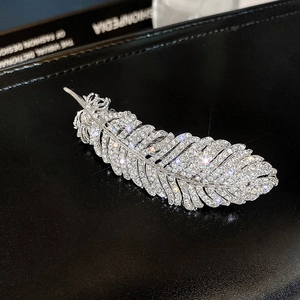 Macro detail of silver feather hair clip with sparkling white zircons on black leather
