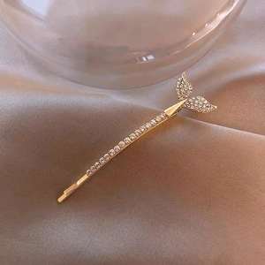 Close-up of golden fishtail hair clip with sparkling rhinestones on champagne silk