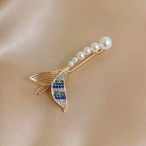 Detail shot of fishtail pearl hair clip with colorful rhinestones on golden silk