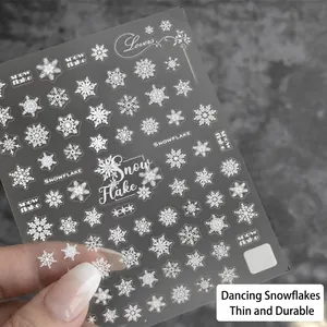 Thin white snowflake nail art stickers with delicate lettering on professional grey background