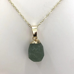 Detail of natural green raw stone pendant with gold plating and fine chain necklace