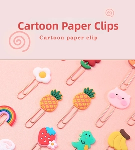 Close-up of cute rose gold cartoon paper clips in strawberry and pineapple shapes
