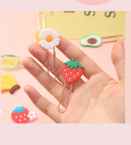 Close-up of hand holding cute daisy and strawberry shaped decorative metal paperclips