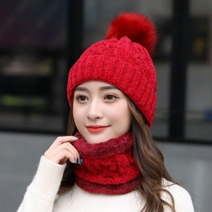 Dettaglio del berretto in maglia di ciniglia rossa con pompon e scaldacollo