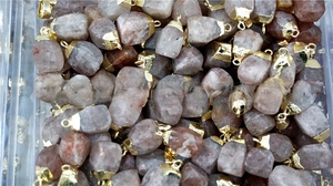 Bulk faceted natural strawberry quartz pendants with gold-plated metal caps in container