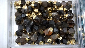 Macro shot of smoky quartz pendants with gold edges piled in a transparent box