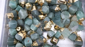 Bulk display of raw green aventurine stone pendants with gold caps in a storage box