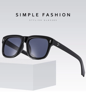 Detailed close-up of black square sunglasses with metallic rivets and glossy frame finish