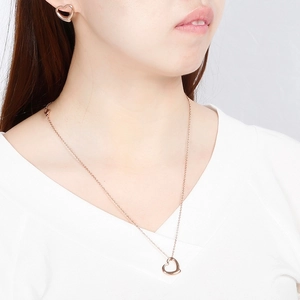 Rose gold stainless steel hollow heart necklace and earrings set worn by a model