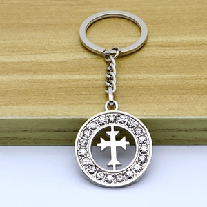 Detailed close-up of a silver metal keychain with a hollow cross and inlaid rhinestones