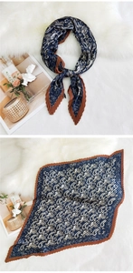 Detail view of navy blue paisley pleated scarf with caramel borders on plush background