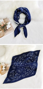 Macro detail of navy blue pleated silk scarf with white paisley pattern on plush carpet