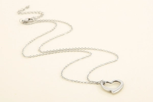 Macro view of polished silver hollow heart pendant on a minimalist necklace chain