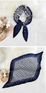 Detail of pleated silk scarf with navy chain print and wavy edges on white fur background
