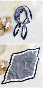 Detail of blue and white houndstooth pleated square scarf on white faux fur background