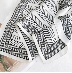 Detail of silk scarf with black and white geometric arrow patterns on soft satin fabric