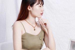 Nahaufnahme von Goldschmuck-Set mit runden grünen Kristallanhängern an einem Model