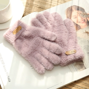 Close-up of pink faux mink touch-screen gloves displayed on a magazine and wooden desk