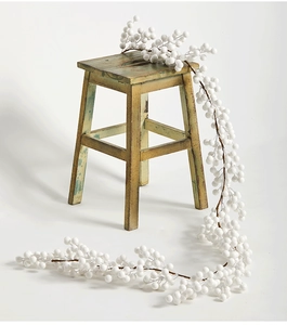 Détail d'une guirlande de baies blanches de 2m drapée sur un tabouret en bois rustique