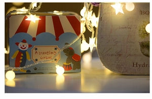 Detail of warm white star and ball LED string lights on circus themed gift box