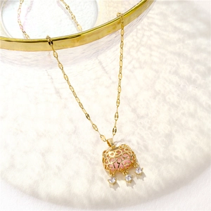 Pink gemstone ruyi lock necklace in gold-plated stainless steel hanging on glass bowl