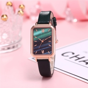 Close-up of rose gold square quartz watch with marble dial and green leather strap