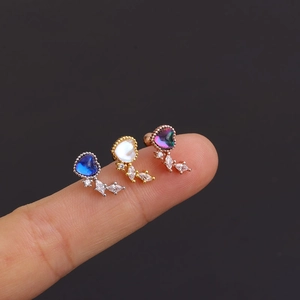 Three surgical steel heart earrings with colorful zircons and leaf charms shown on fingers