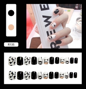 Detail view of cow print press-on nails set including cartoon motifs and black patterns