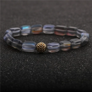 Elegant moonlight stone bead bracelet with a gold pavé crystal charm on a dark background