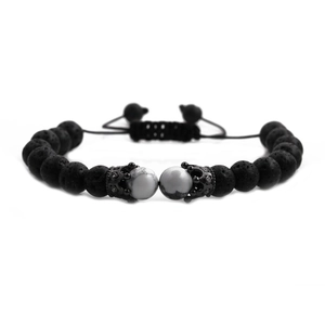 Macro detail of lava stone beads and metal crown charm on adjustable braided bracelet