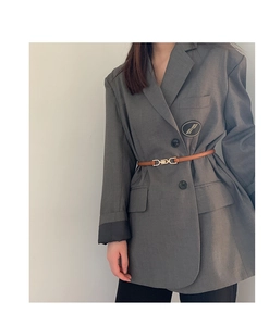 Slim brown leather waist belt with gold buckle styled over a grey blazer for women