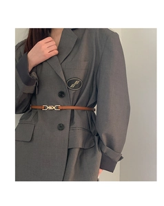 Close-up of a slim brown leather belt with a gold metal buckle on a grey blazer