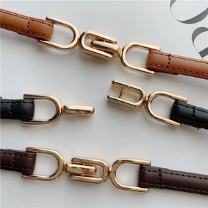 Three thin leather belts in brown, black, and coffee with gold U-shaped buckles