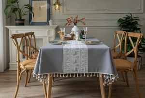 Close-up of gray cotton linen tablecloth featuring white reindeer ribbon and fringe trim