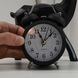 Modern 3 inch black metal mechanical twin bell alarm clock held in hand with white face