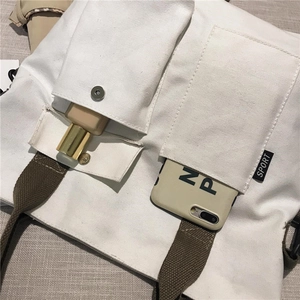 Close-up of white canvas tote bag side pockets showing phone and makeup storage