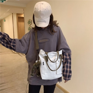 Lifestyle shot of large white canvas tote bag worn by a model in casual streetwear outfit
